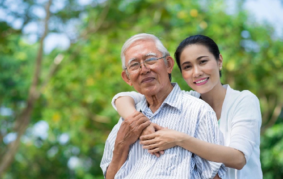 A woman and an older man are smiling for the camera.