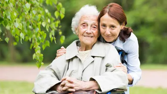 A woman hugging an older lady in a wheelchair.