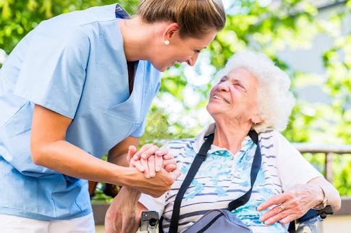 A nurse holding hands with an elderly woman.