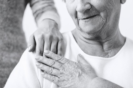 A person holding their hands over the shoulder of another person.