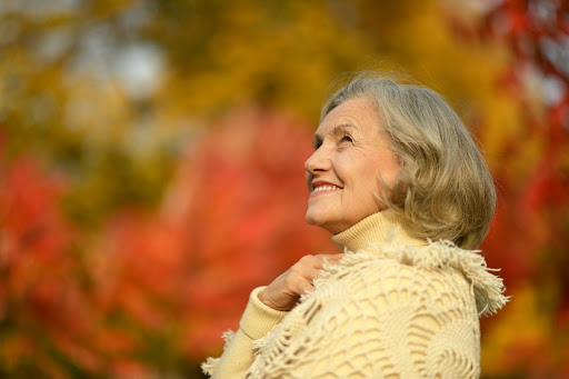 A woman in a yellow jacket looking up at the sky.