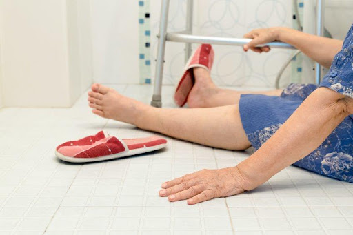 An older person on the floor of a bathroom.