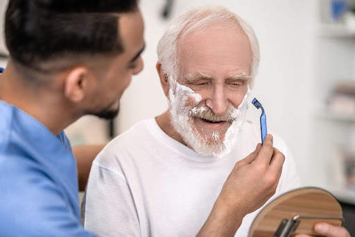 A man with a beard is shaving another man 's face.